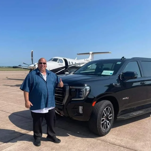 A guide standing by a black SUV next to a small plane
